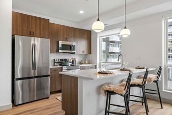 Modern kitchen with a stainless steel refrigerator, wooden cabinets, and a white island
